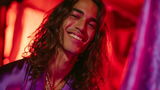 young Brazilian male model, wearing purple open robe, has long hair, smiling, luscious atmosphere, highly detailed face and eyes, fashion photography, vogue editorial, neon red and velvet lighting and color palette --ar 16:9 --style raw --v 6.0