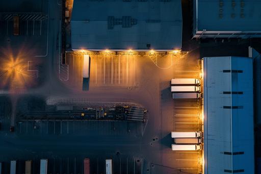 Aerial view of goods warehouse at Night. Logistics center in industrial city zone from above. Aerial view of trucks loading at logistic center, , --ar 3:2 --style raw --stylize 50 --v 6.0