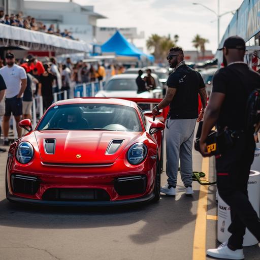 A big race car event, person looking at the camera getting ready to step inside race car, pit crew, race track, car tires, Porsche 911 GT3, trophy, race track, pit lane, fans looking at car behind red velvet rope