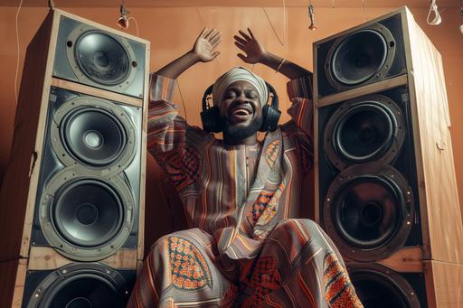 Dramatic low angle shot of full body shot of cool black Muslim man, wearing African Muslim attires, excited, happy, fun, energetic, relaxed leaning on 3 huge speakers, with huge headphones, laughing, smiling into the camera, in a studio photoshoot in Lagos --ar 3:2 --v 6.0 --s 50