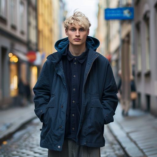 Male Model, Swedish aged 23 with blond hair. He is part of a campaign shoot for a Scandinavian brand. Model is wearing a short hooded carcoat in retro blue, fabric is a cleanmodern nylon . Very clean and minimal outfit. Underneed the jacket you can see a dark blue shirt tucked in a dark grey pleated pant. The model is standing in an street in Stockholm with minimal light grey buildings. Total picture needs to feel very natural, minimal and fresh. Shoot is in May, so lots of light and freshnes