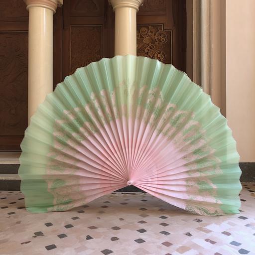 a giant hand spanish folding fan, made out of light pink and green layerd organza, set design for opera outdoors, saluzzo opera academy, realistic