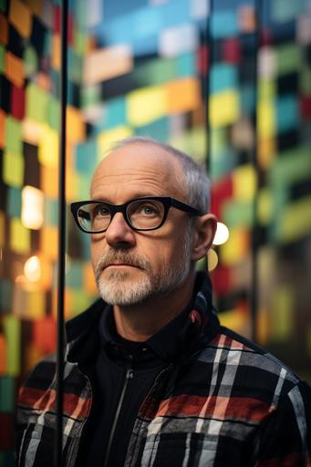 a gray man in glasses in front of a metal wall, in the style of tom fruin, close-up, liam gillick, ettore sottsass, photographic weavings, photo taken with provia, transparent/translucent medium --ar 85:128