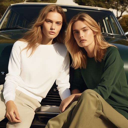 a polo Ralph Lauren women model with blonde long hair sitting on a vintage dark green car, the model is wearing white sweatshirt. Next to the car is standing another model with brown hair and blue eyes wearing a black t shirt and a long skirt, and leaning against the car