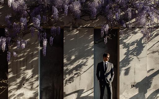 dramatic shot of a wisteria art gallery showcasing maximalist wisteria overgrown architectural luminogram endless rocks portals photography luminosity in Milan, by elsa bleda, minimal Sisyphean male in dior suit, natural sunlight and dark shadows --ar 8:5 --stylize 150 --v 6.0