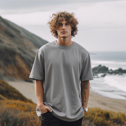 guy in the nature wearing a grey baggy tee with no design on it with a stunning background surf skate style vibes