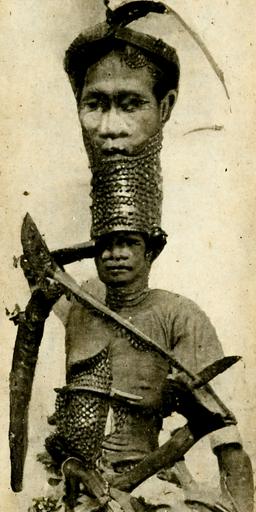 vintage photograph of moro muslim, island of mindanao, full battle armour, augmented with thick Liana vine wrappings thick enough to protect from 0.45 calibre ammunition, wielding Very Nice Philippine Mindanao Horsehoof Moro Kris Sword with Layered Steel Blade in one hand and machete in the other, 1910 --h 512