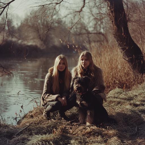 two twins fit young blond woman next to each other with a black Belgian Griffon on a walk next to a river. Front view slightly from below. Grass and trees around. Winter sunny day. --v 6.0