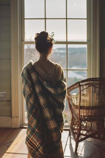 wide shot of woman standing on wooden floor in front of window overlooking new england marine landscape, seen from behind. the woman wears a plaid blanket around her. the woman wears a brunette updo with a light blue ribbon. she is standing next to a rattan chair. color photography shot on kodak portra with 60s muted color palette --ar 2:3 --v 6.0